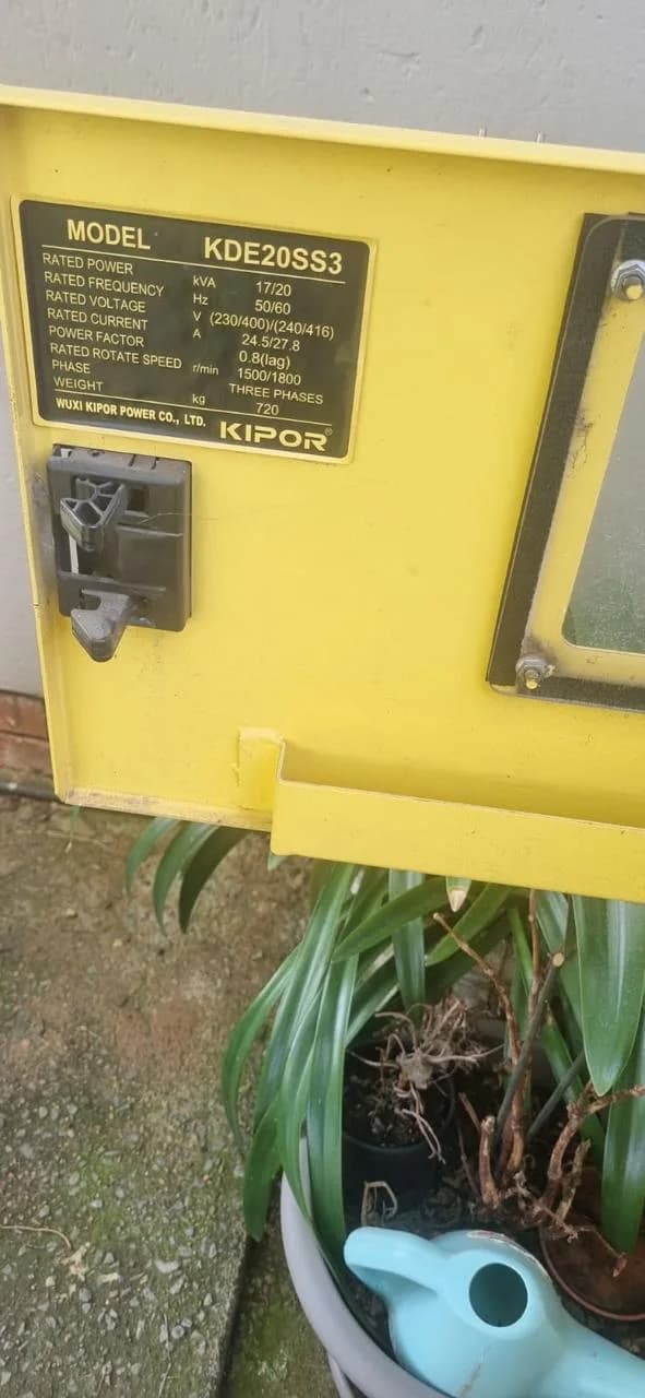 Kipor KDE20SS3 rating plate on a yellow canopy door listing 17/20 kVA, voltage, current and 1500/1800 rpm