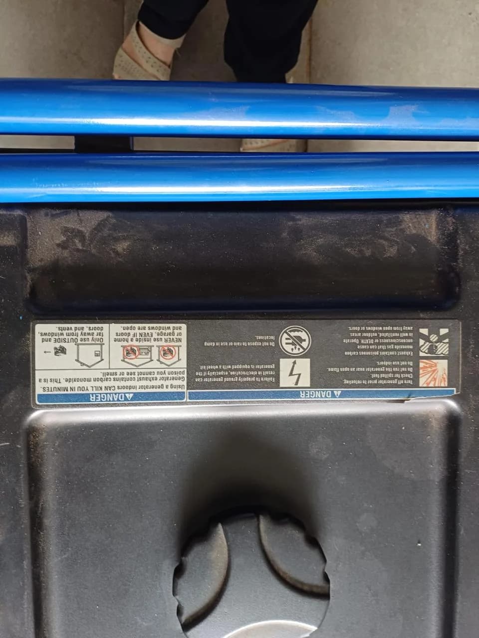 Top of a portable generator with a blue frame and an upside-down carbon monoxide danger label