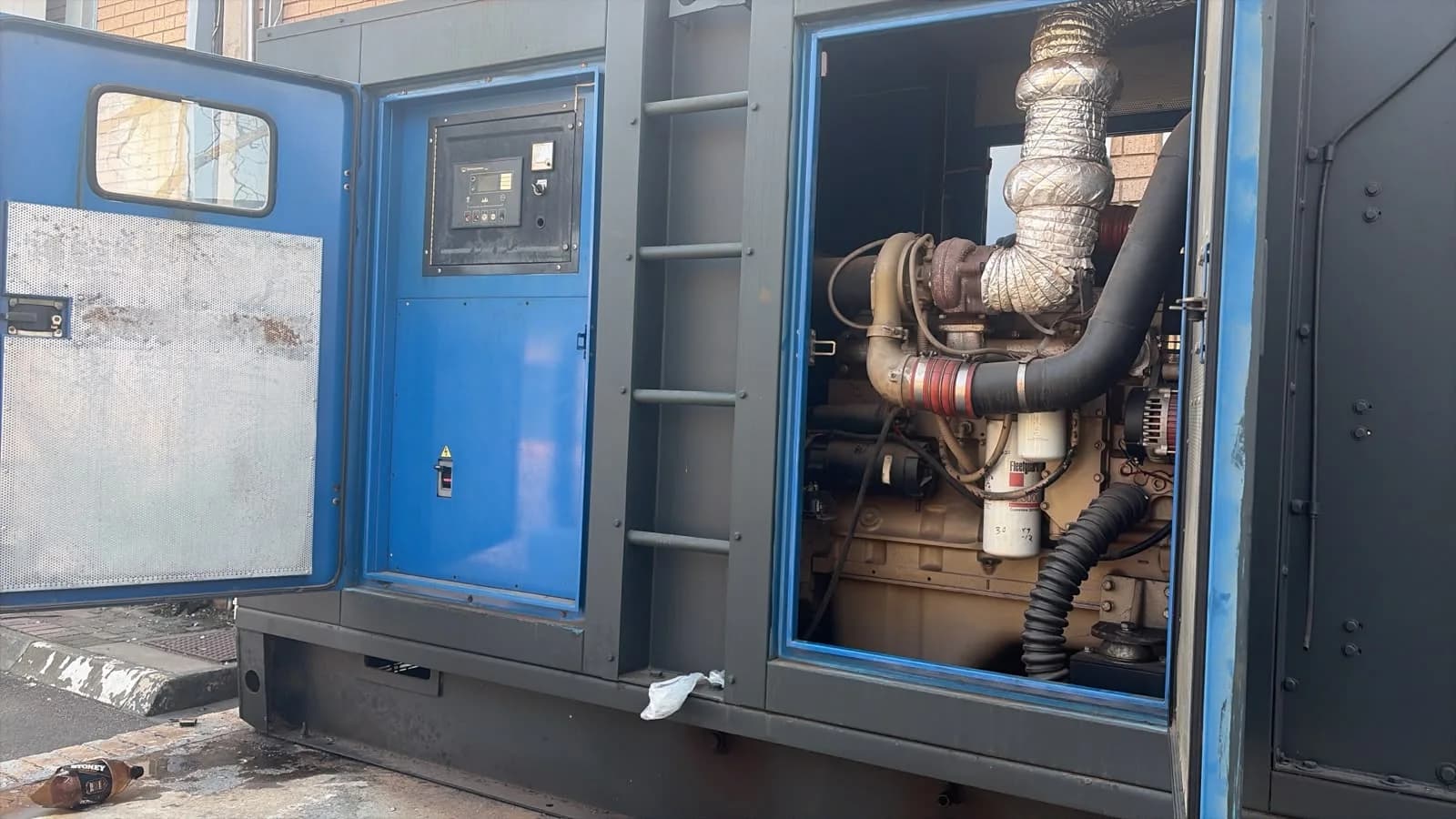 Large dark grey canopy open on a turbocharged diesel engine with Fleetguard filters, controller on a blue door panel