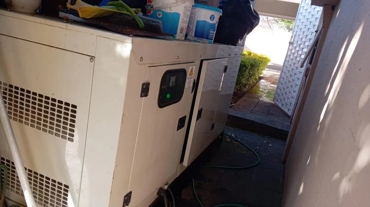 White canopied diesel generator with controller window squeezed into a narrow side passage, buckets on top