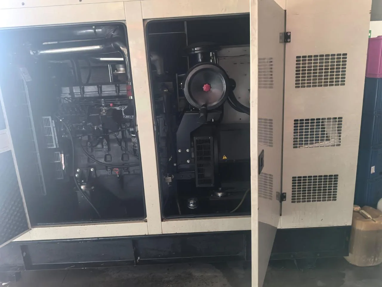 Cream canopy with service doors open on a black diesel engine and air filter, a fuel can at the side