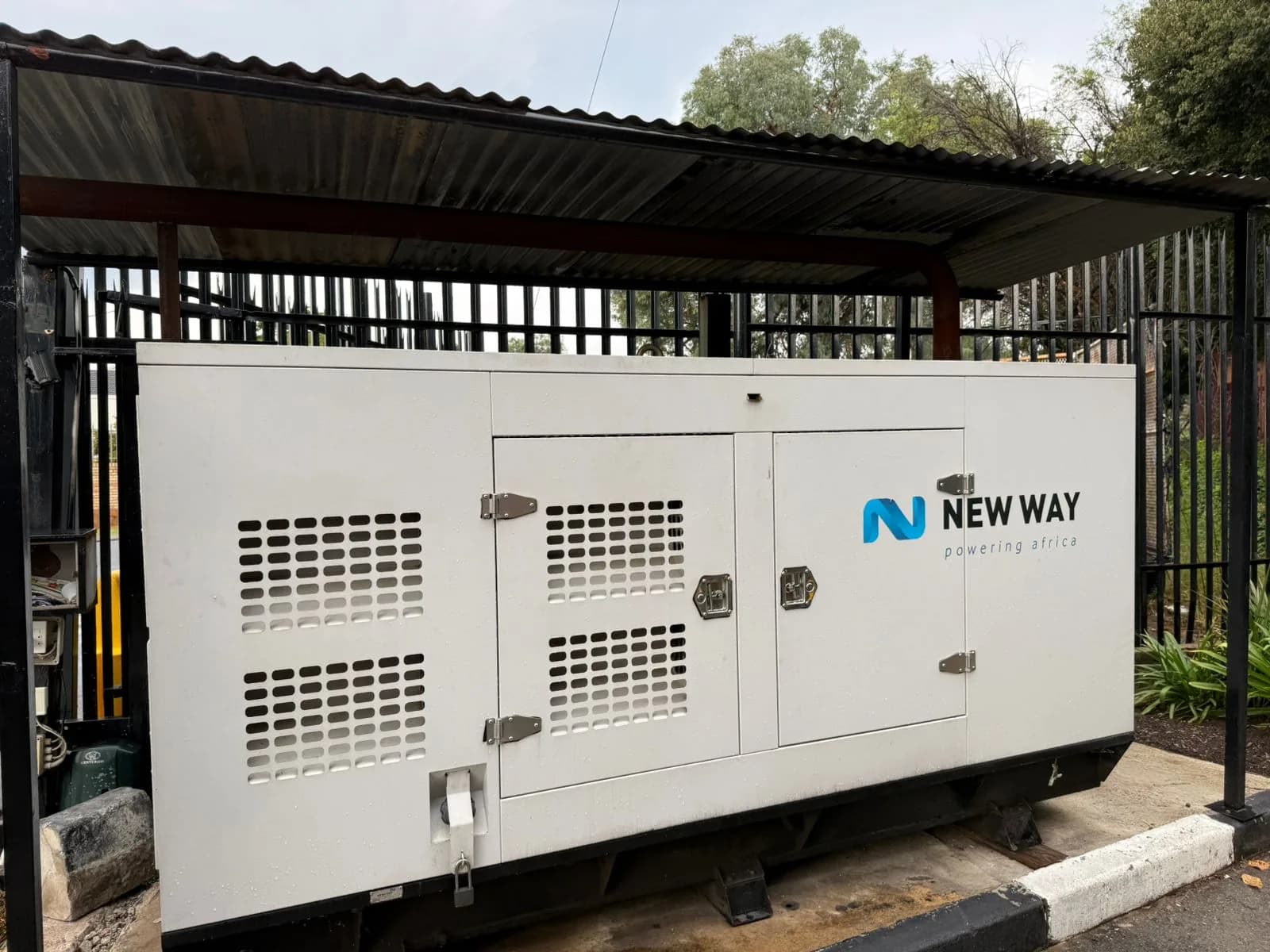 White New Way canopied diesel generator under a steel carport inside a black palisade fence