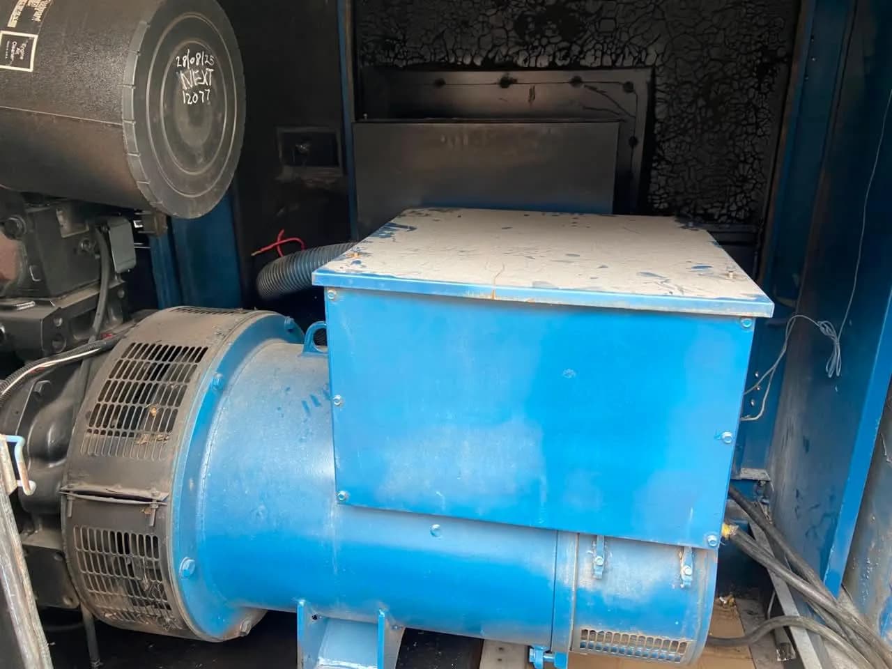 Blue generator alternator inside a canopy, with the service date and next-service hours written on the air filter