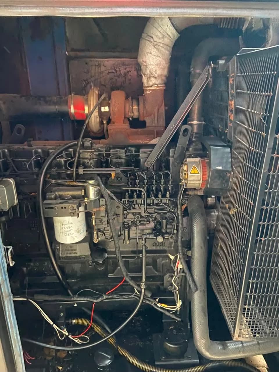 Six-cylinder turbo diesel engine with injection pump, wiring and a dated fuel filter behind a radiator guard