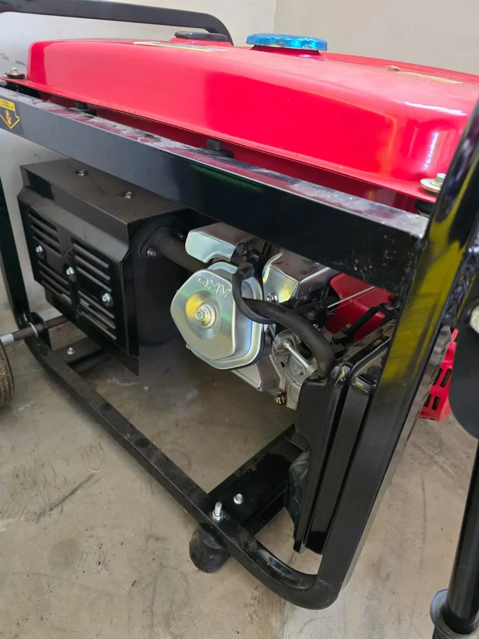 Red-tanked portable generator with an OHV engine and black muffler in a black tube frame