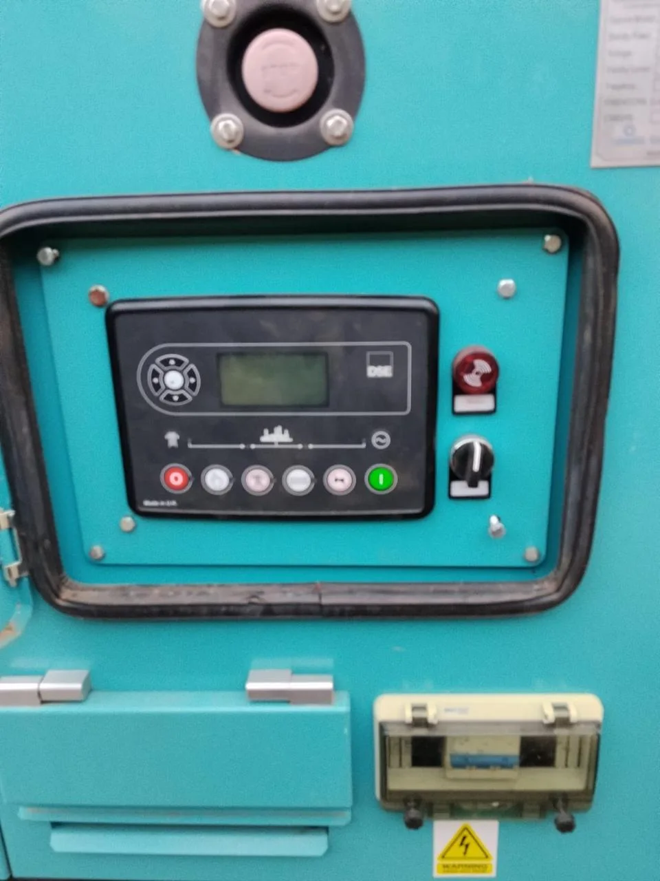 DSE generator controller, emergency stop and key switch on a teal canopy, with the breaker box below