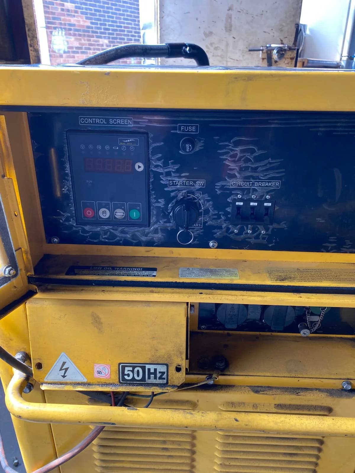 Yellow silent diesel generator control panel with a basic digital controller, starter switch and circuit breakers