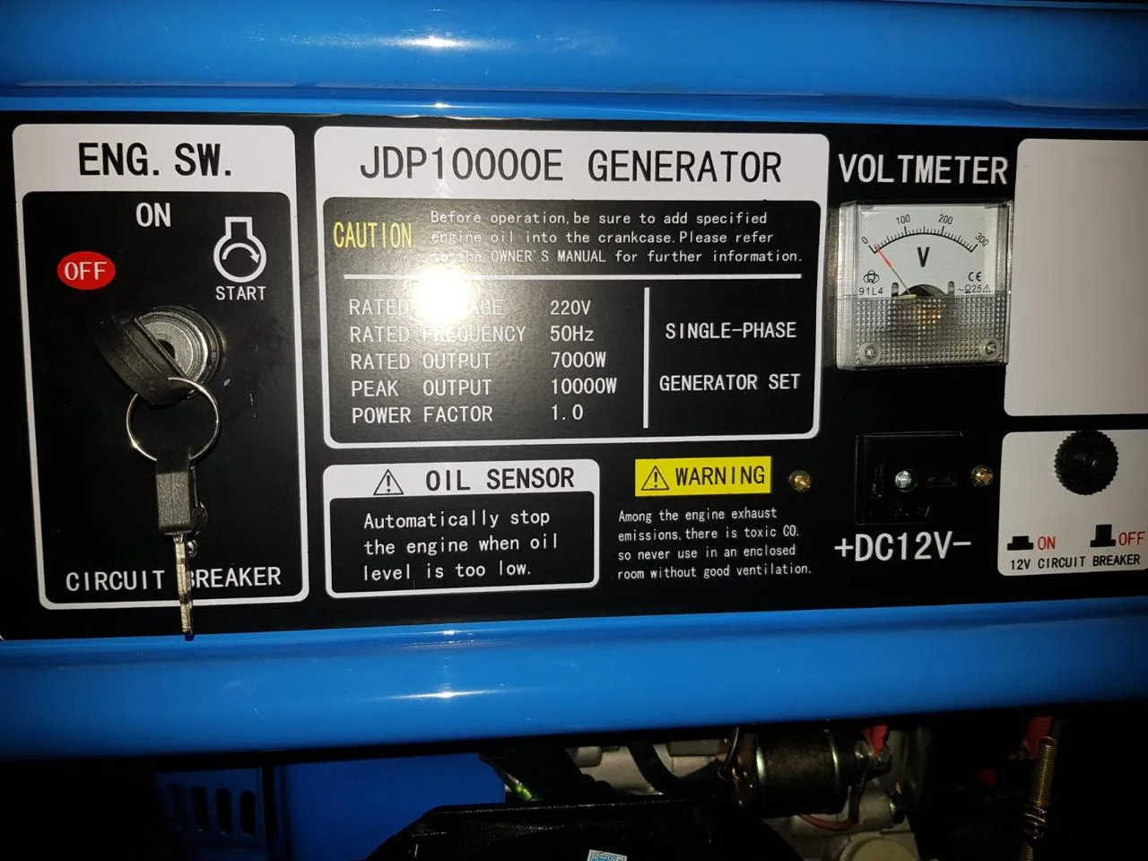 Control panel of a blue JDP10000E single-phase generator showing key switch, voltmeter and 7000 W rating