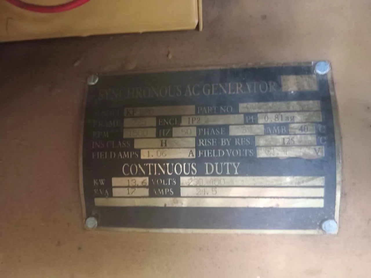 Brass synchronous AC generator plate marked continuous duty, 13.6 kW and 17 kVA, on a cream panel