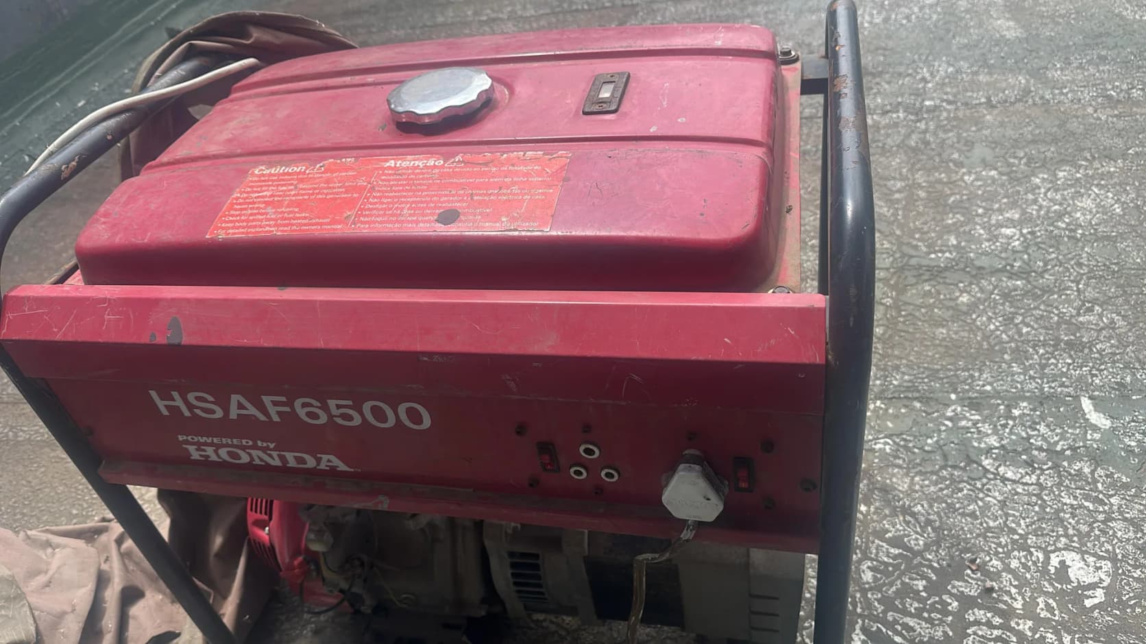 Faded red HSAF6500 petrol generator powered by Honda, in a black tube frame on a concrete floor