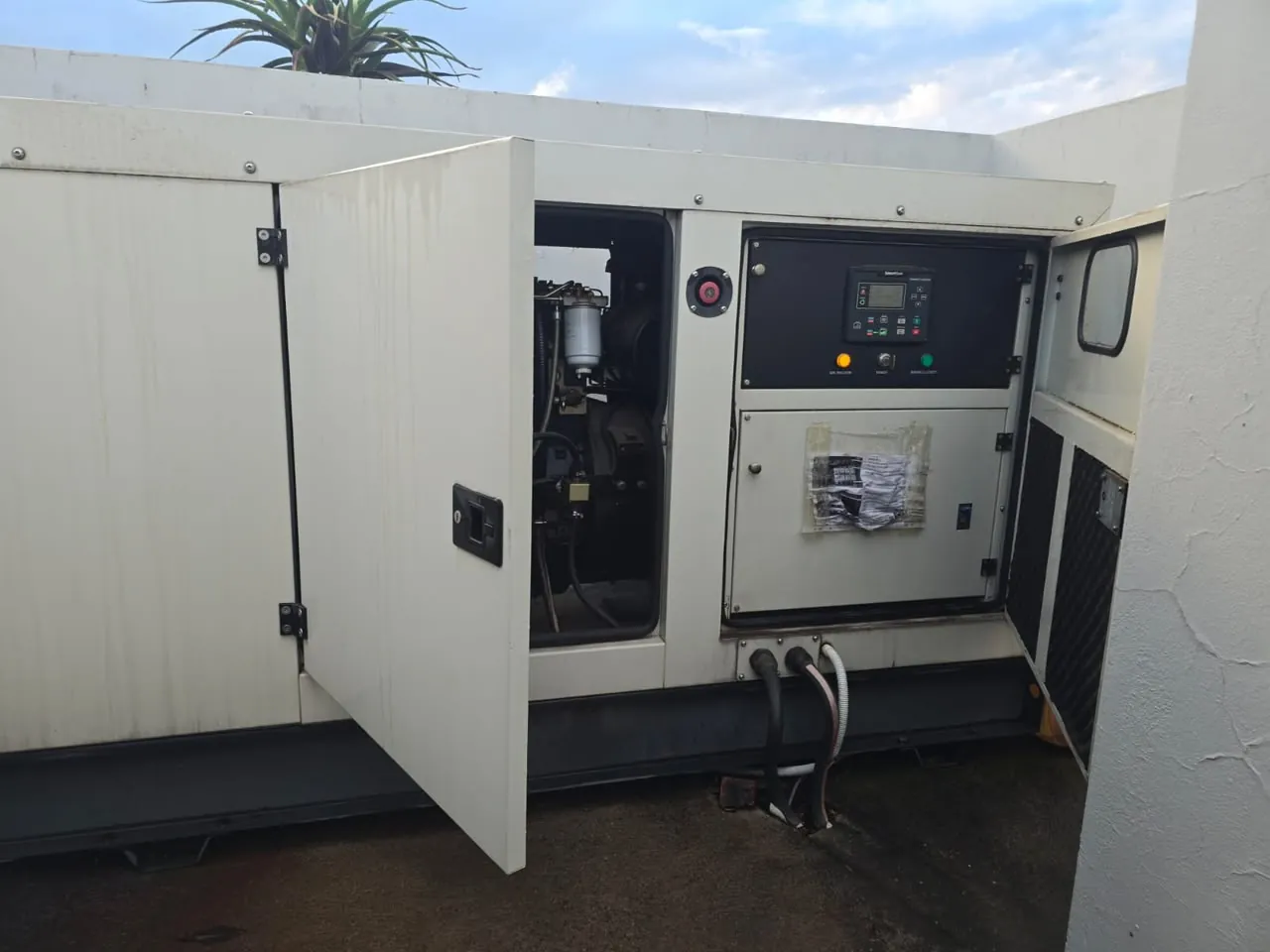 Diesel standby generator with its service doors open, showing the fuel filter and a SmartGen controller