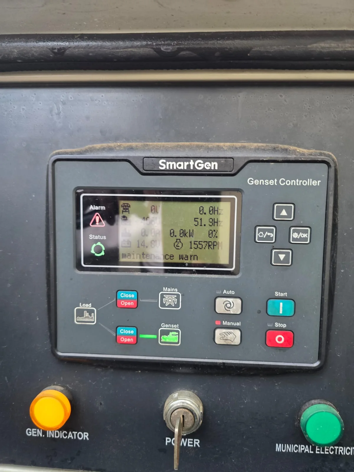 SmartGen genset controller showing a maintenance warning at 1557 rpm, with key switch and indicator lamps